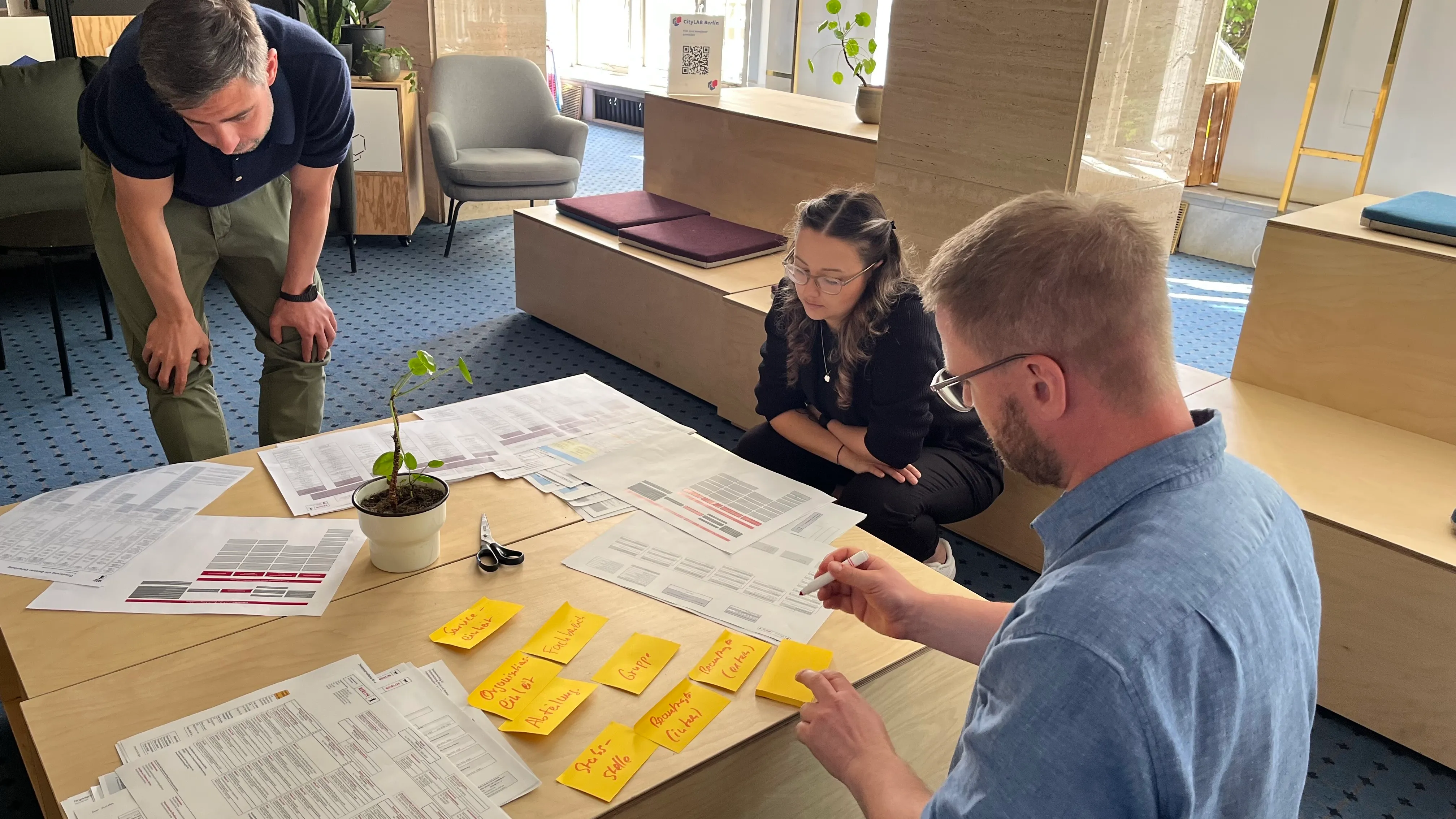 People looking on a table with post its on it.